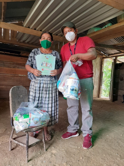 Zwei Mitarbeitende der Organisation Tzuul Taq'a verteilten gleichzeitig Informationen zu Covid und dringend benötigte Nahrungsmittel.